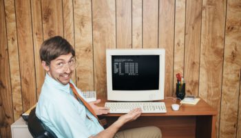 Büroangestellter sitzt vor seinem PC - Bürojob in der Vergangenheit - Computer - Humor